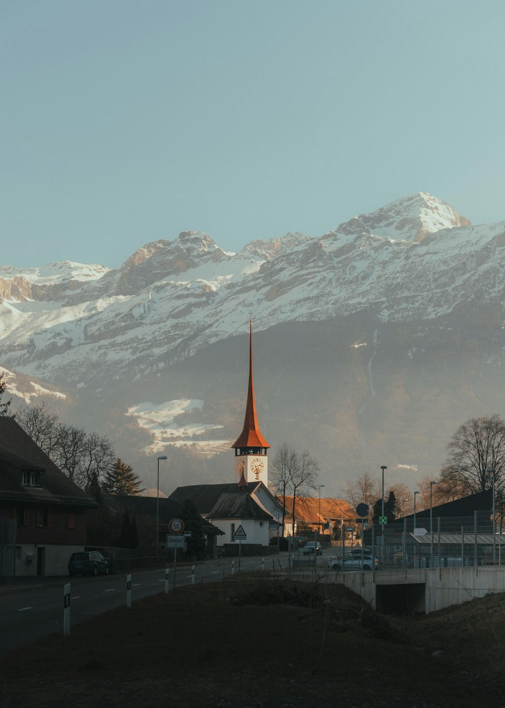 a church with a steeple in front of a snowy mountain