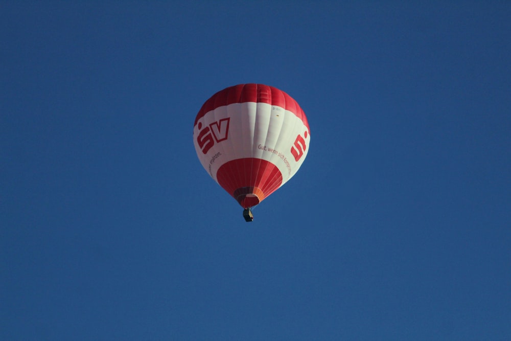 a red and white hot air balloon flying through a blue sky