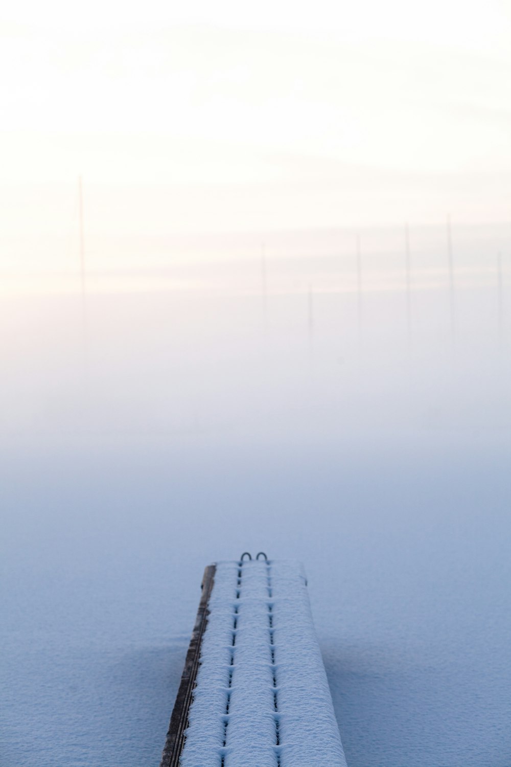 a snow covered bench sitting in the middle of a snow covered field