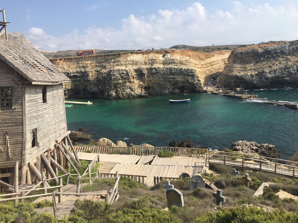 a wooden building sitting on top of a cliff next to a body of water