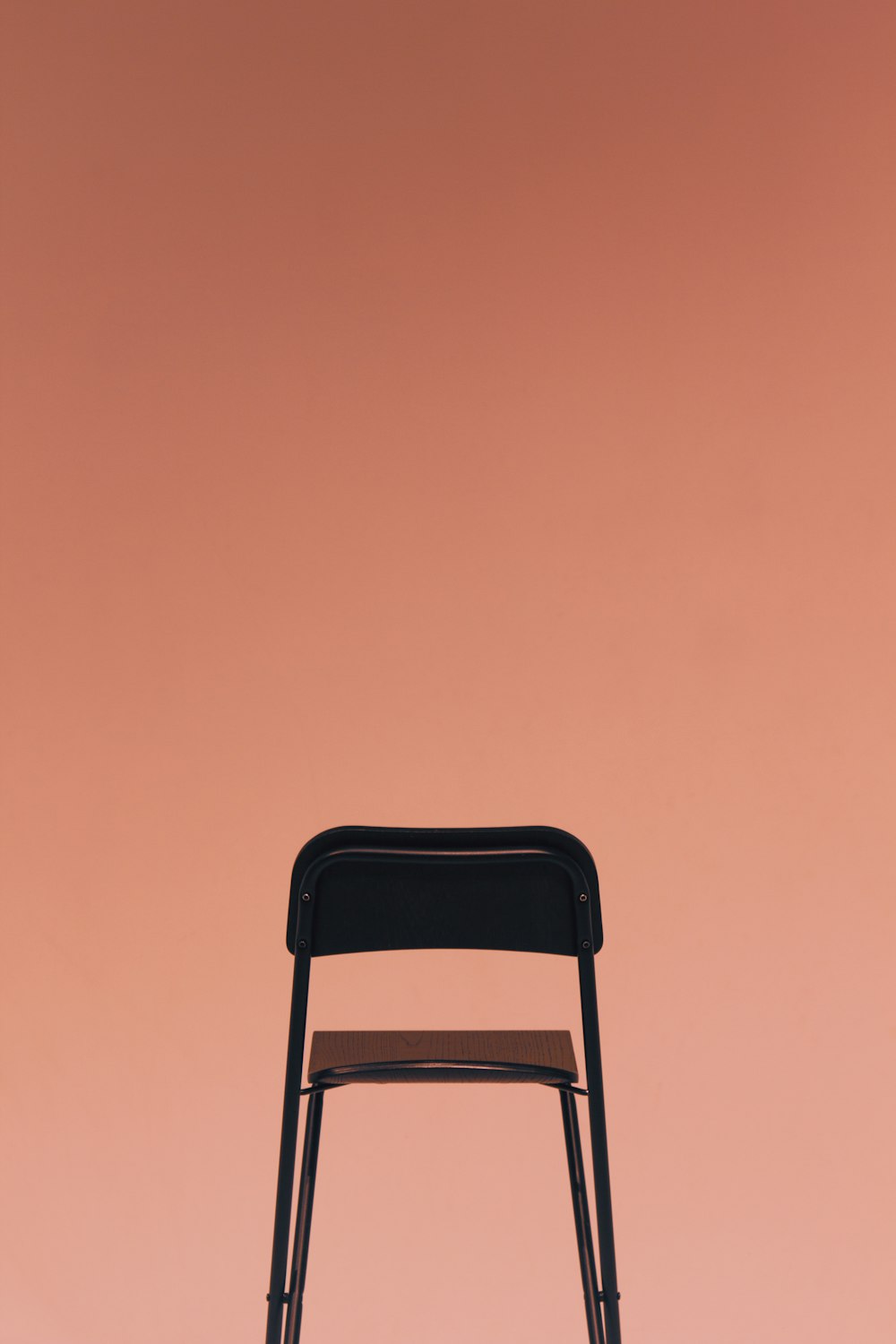 a black chair against a pink background