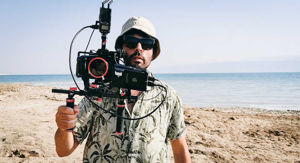 a man holding a video camera on a beach