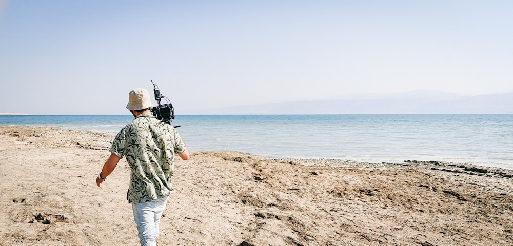 a man walking on a beach with a camera strapped to his back