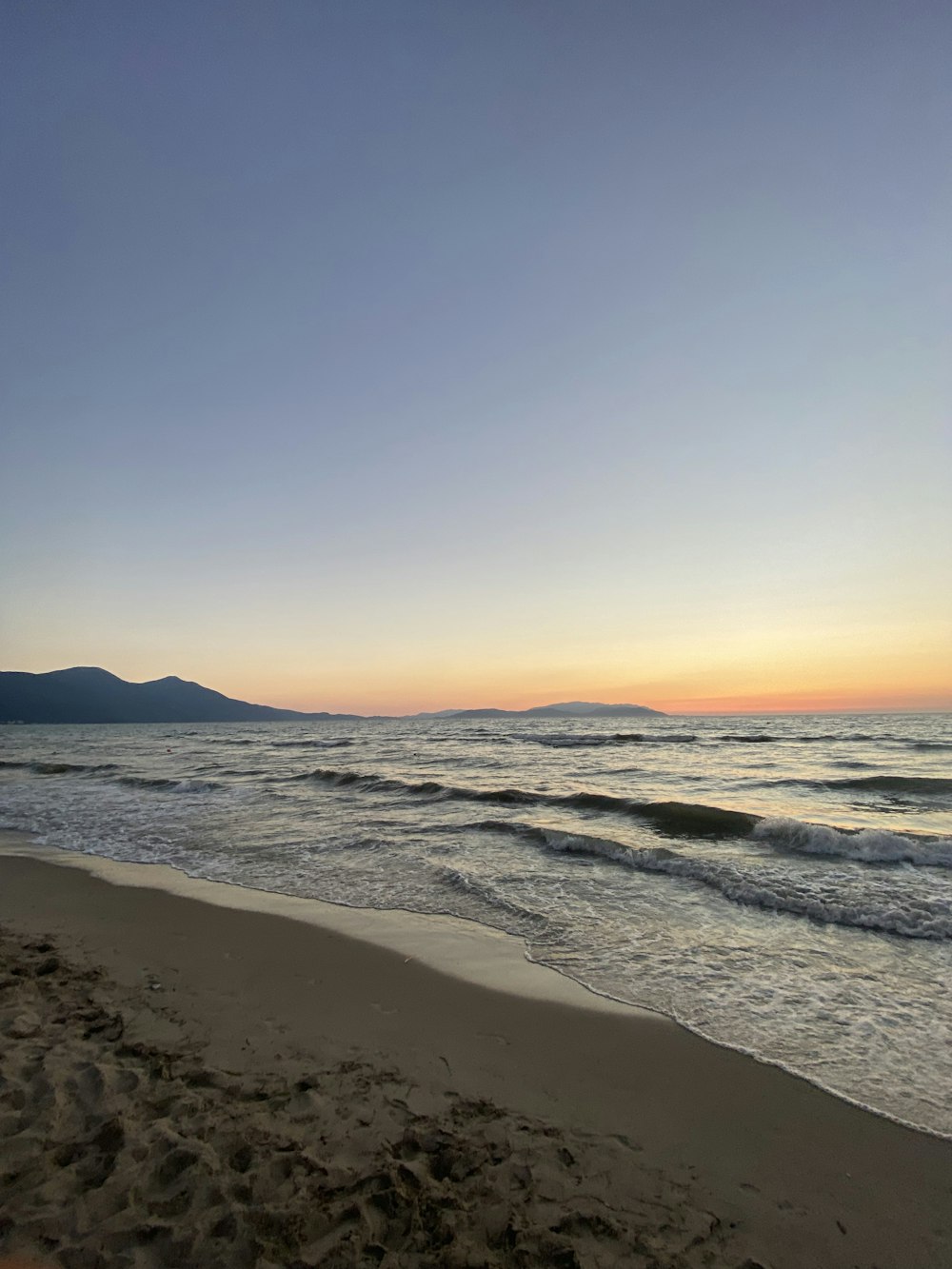 a view of the ocean from a beach at sunset