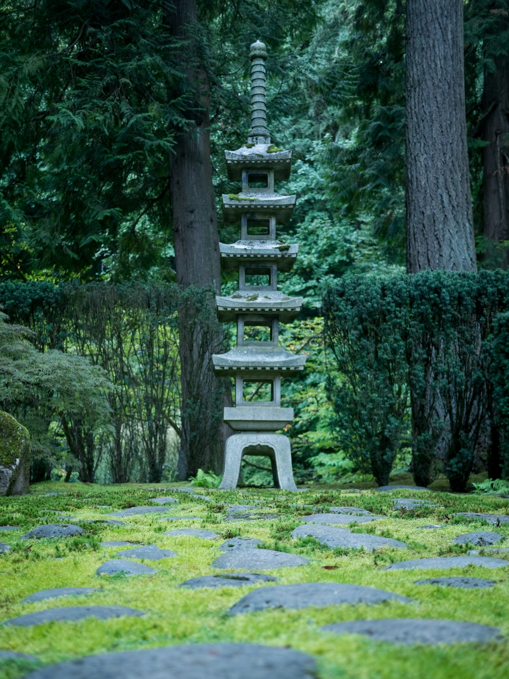 a stone pagoda in a garden surrounded by trees