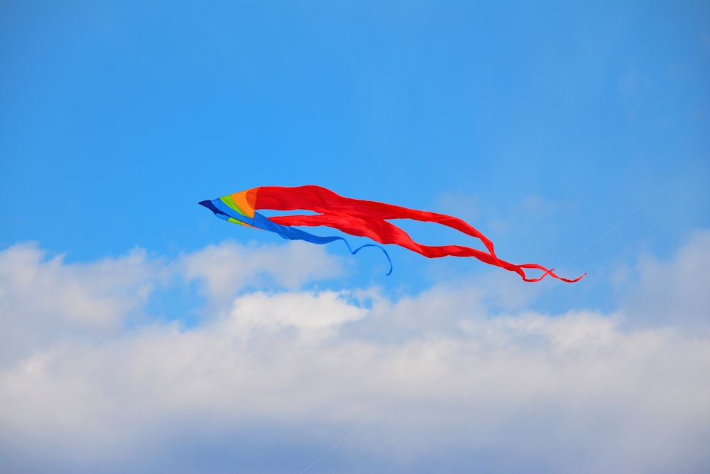 a colorful kite flying through a blue cloudy sky