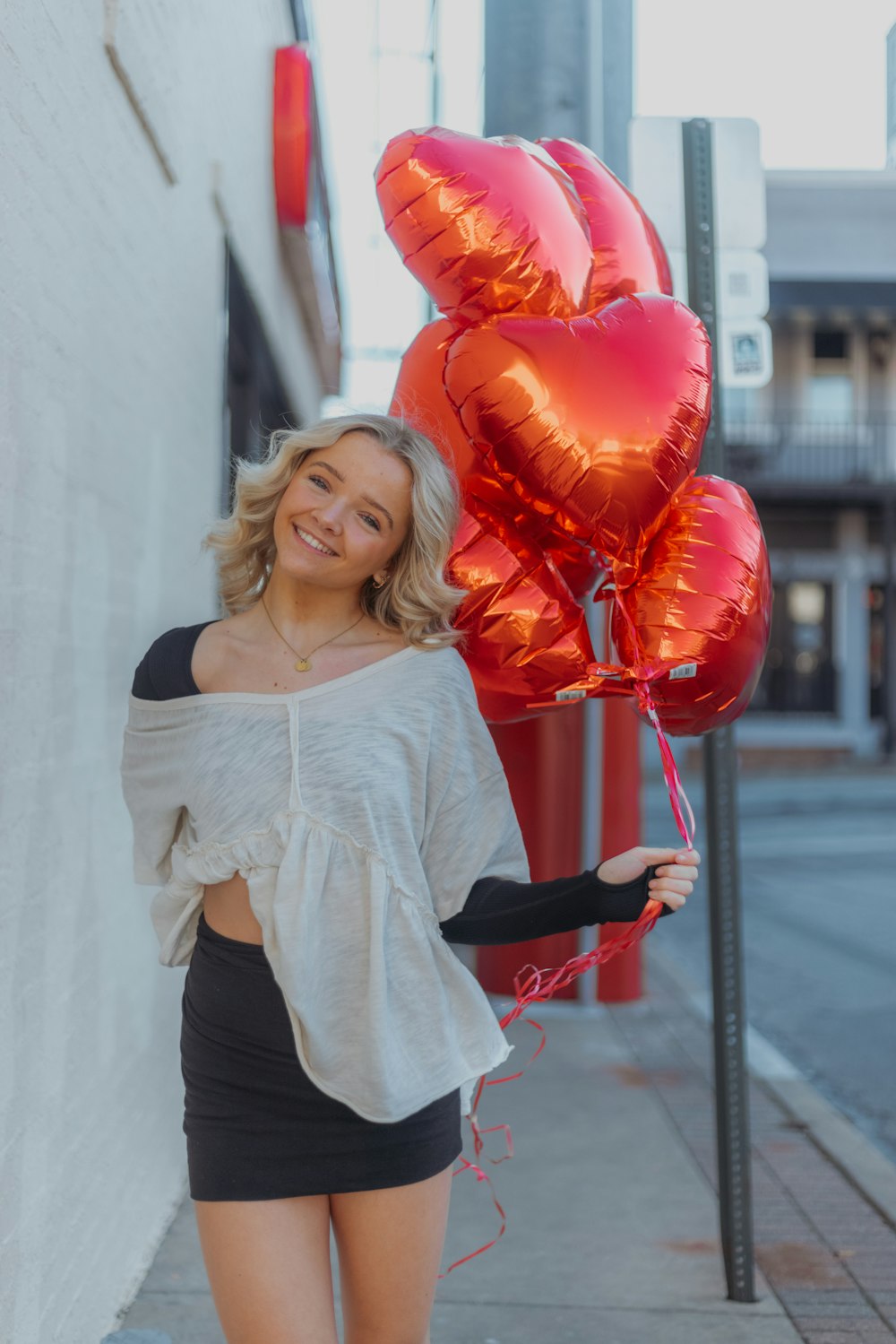 a woman holding a bunch of red heart shaped balloons