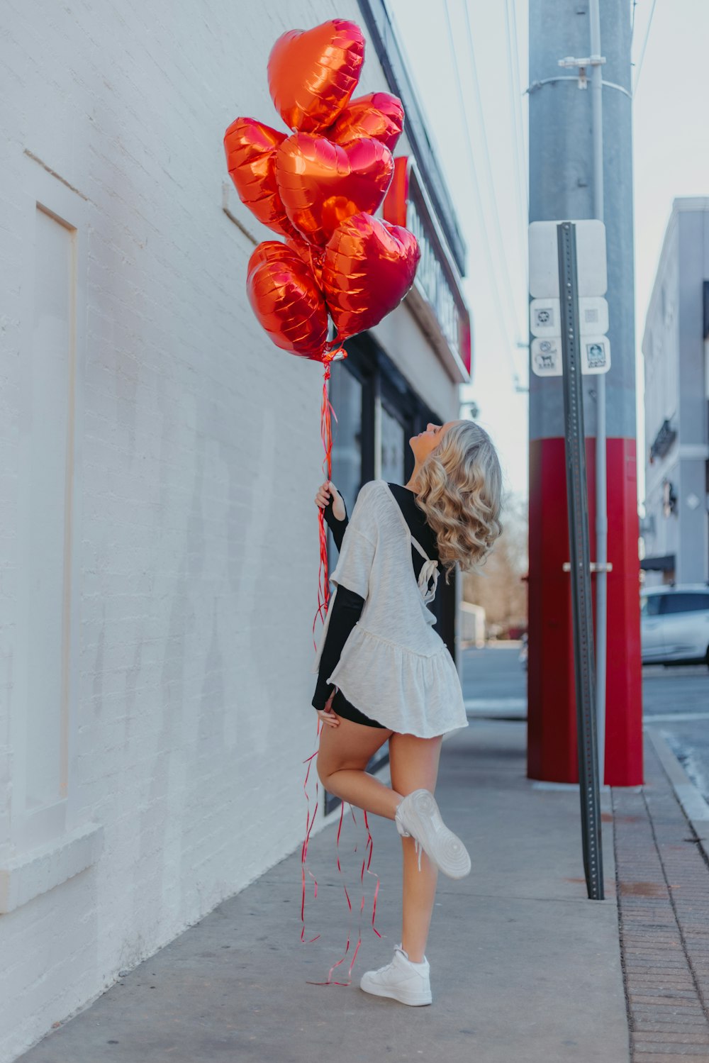 a woman holding a bunch of red balloons