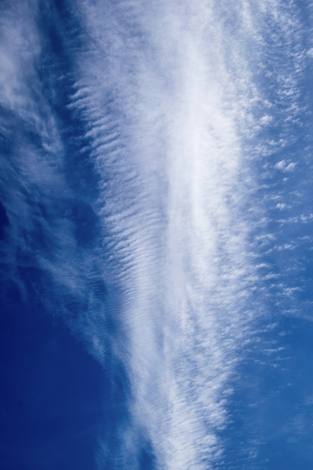 a plane flying through a blue sky with white clouds