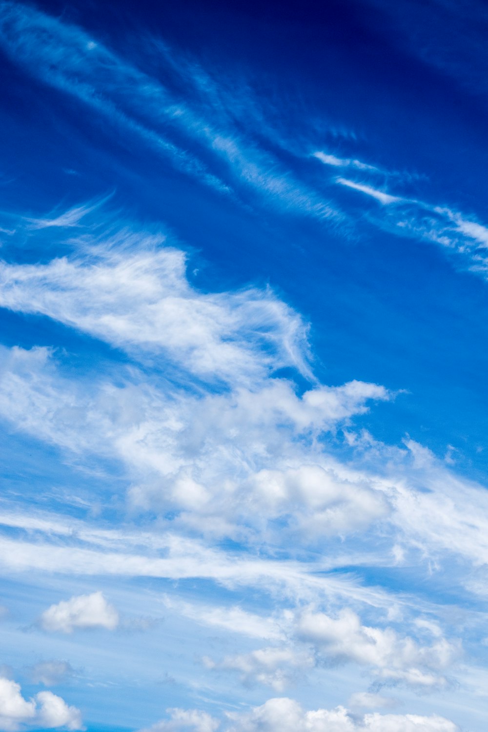 a plane flying through a blue cloudy sky