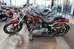 Several sleek, red motorcycles are parked in a showroom with polished concrete floors. The motorcycles have chrome accents and black seats, and are lined up in an orderly fashion. The showroom has large windows and other motorcycles visible in the background.