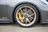 Side view of a Porsche GT3RS racing on a track with 4s racing 9rs wheels in matt gold finish.