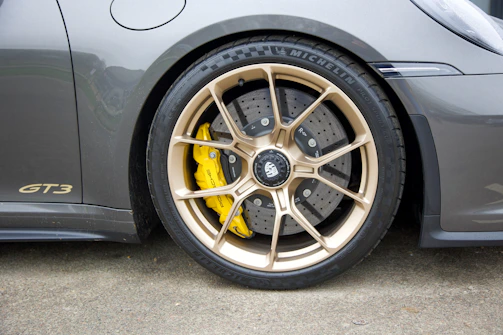 Side view of a Porsche GT3RS racing on a track with 4s racing 9rs wheels in matt gold finish.