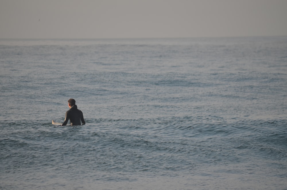 a person sitting on a surfboard in the ocean