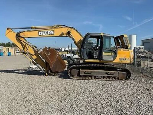 A rugged heavy equipment tire resting on a construction site with a yellow excavator in the background.