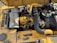 A detailed view of a yellow industrial engine with various components, including hoses, a fan belt, and metallic parts. There is a prominent use of black and yellow materials, and the engine is set against a sunny background which casts shadows on its surface.