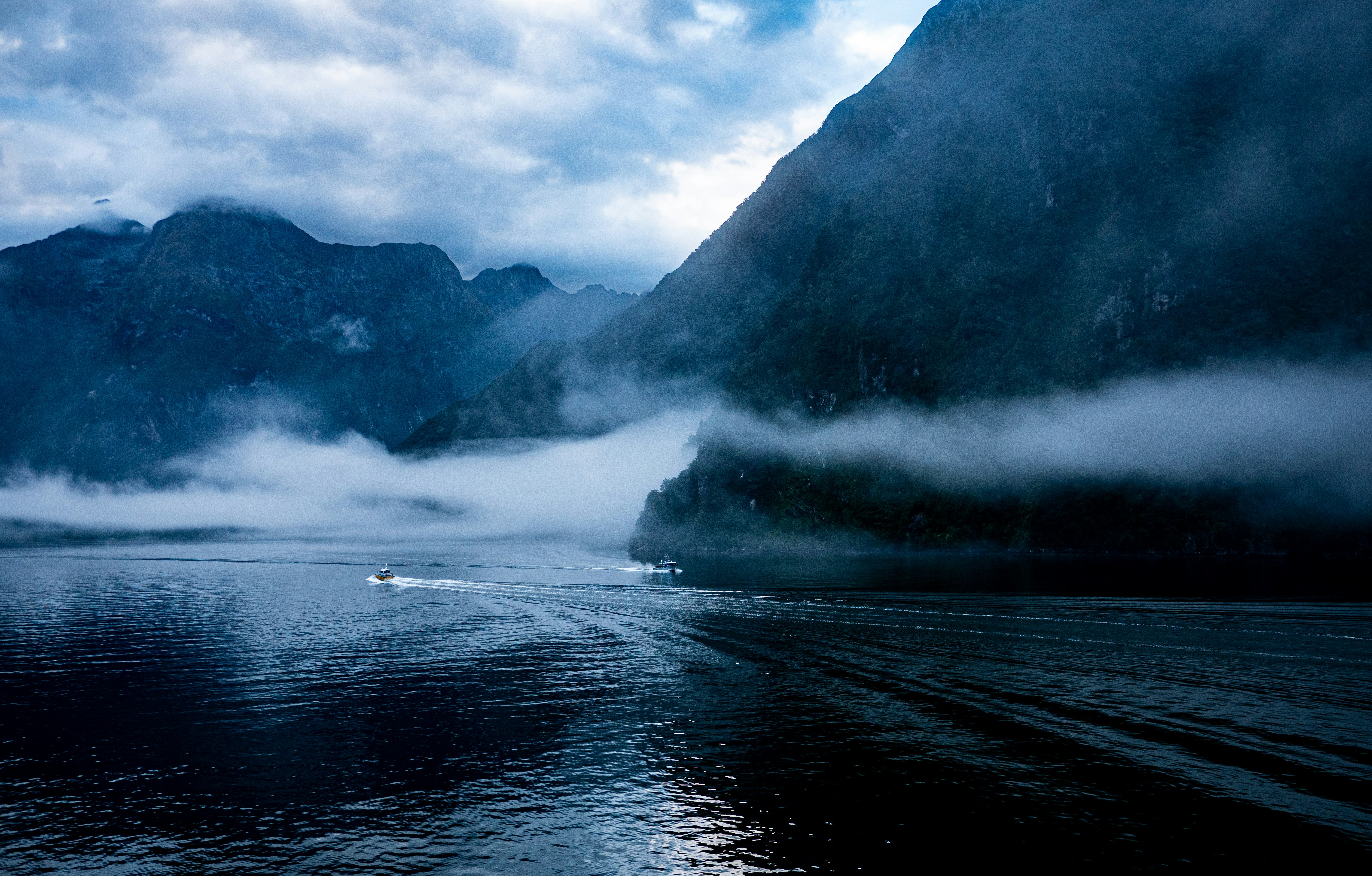 a boat traveling on a body of water with mountains in the background
