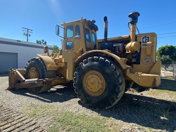 A rugged little tractor at work moving gravel on a sunny lot.