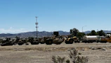 Heavy machinery and workers coordinating logistics at a large infrastructure project under a clear sky.
