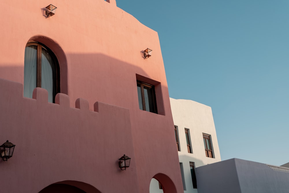 a pink building with two windows and a red door