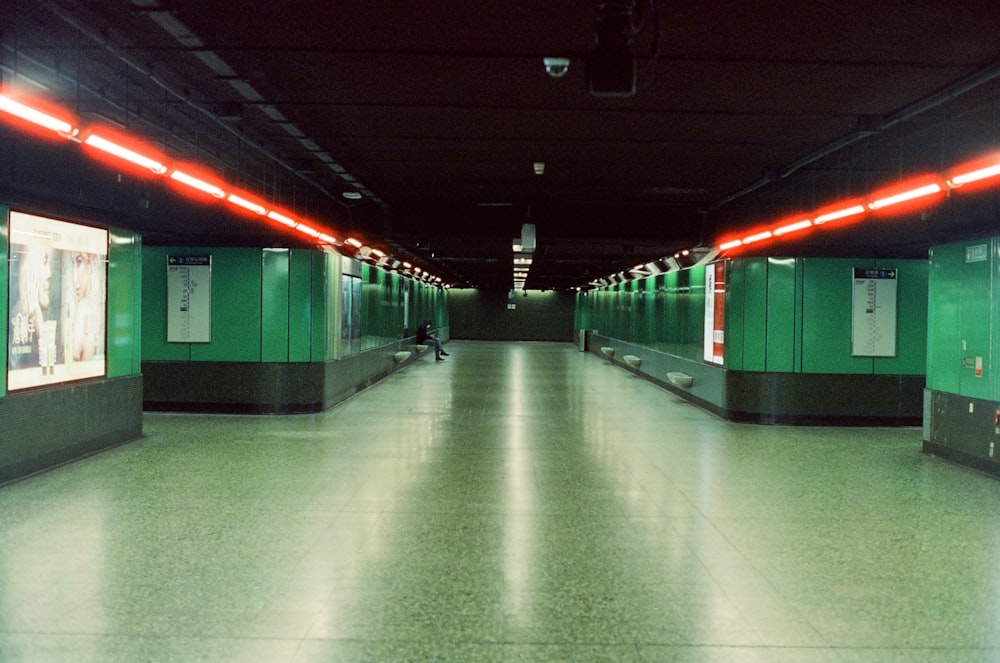 a long hallway with green stalls and red lights
