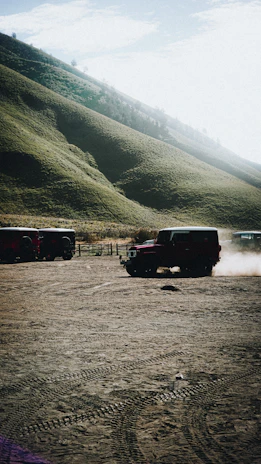 A muddy 4x4 vehicle climbing a rocky hill under a cloudy sky.
