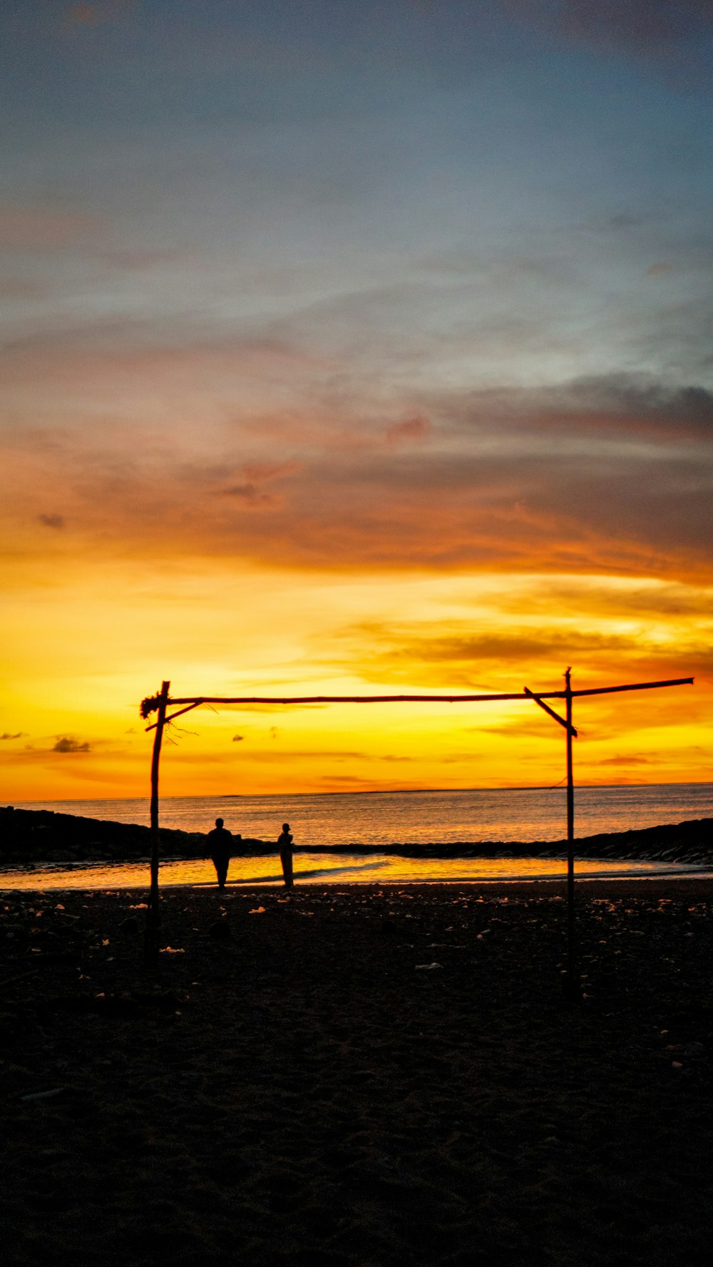 a couple of people standing on top of a sandy beach