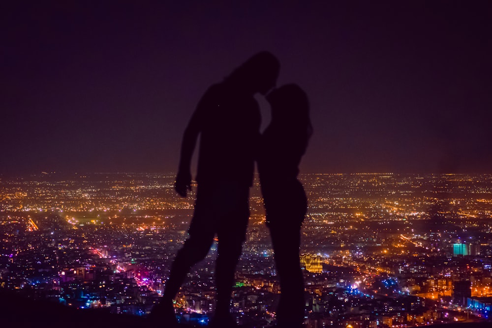 two people standing on top of a hill at night