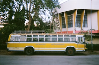 a yellow and white bus parked in front of a building