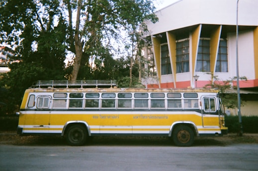 a yellow and white bus parked in front of a building