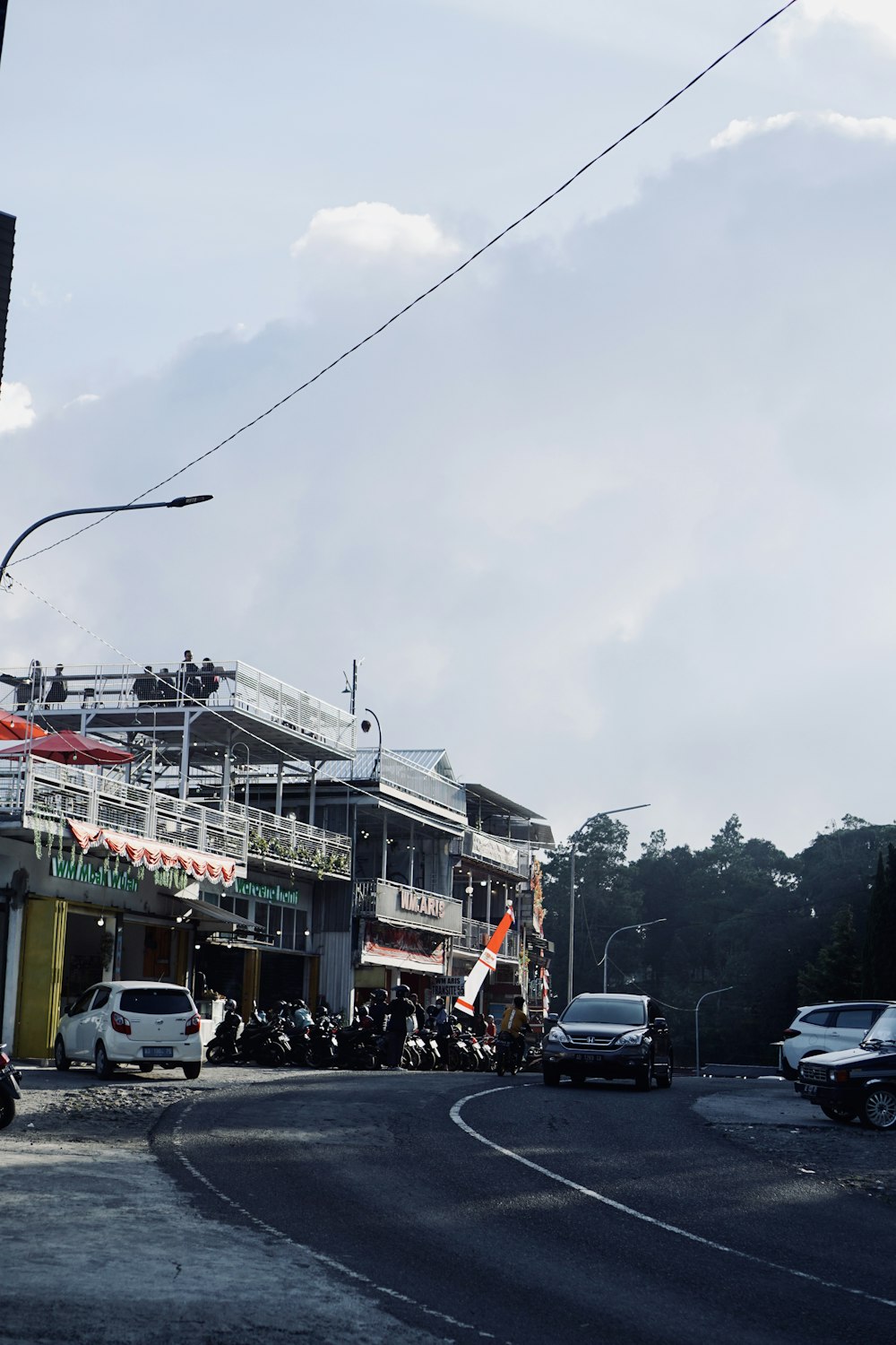 a city street with cars and motorcycles parked on the side of the road