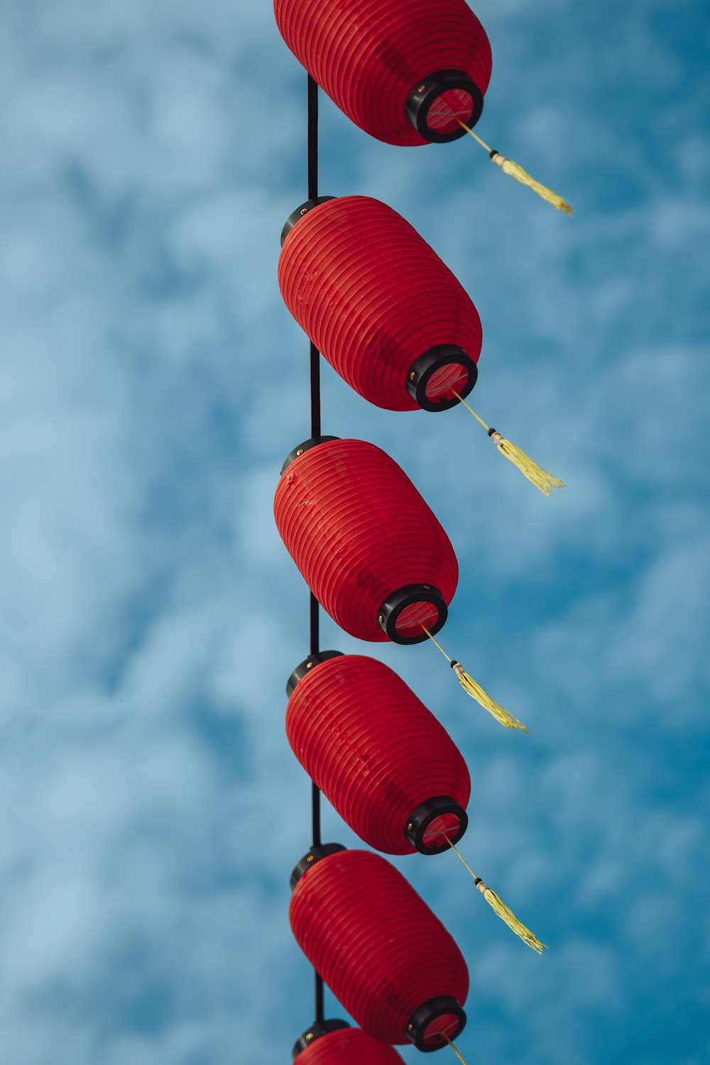 five red lanterns hanging from a pole in the sky