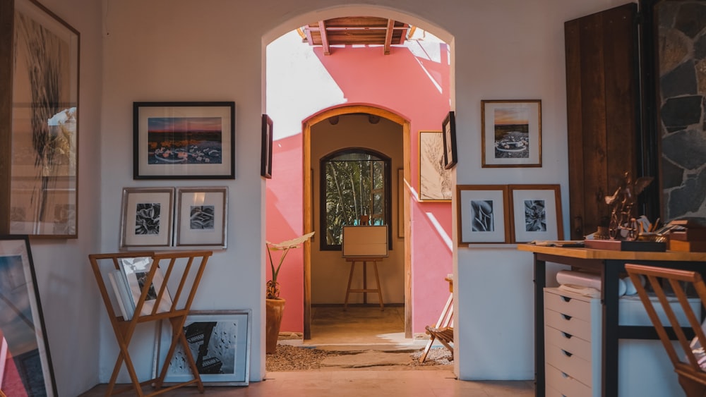 a hallway with a pink wall and pictures on the wall