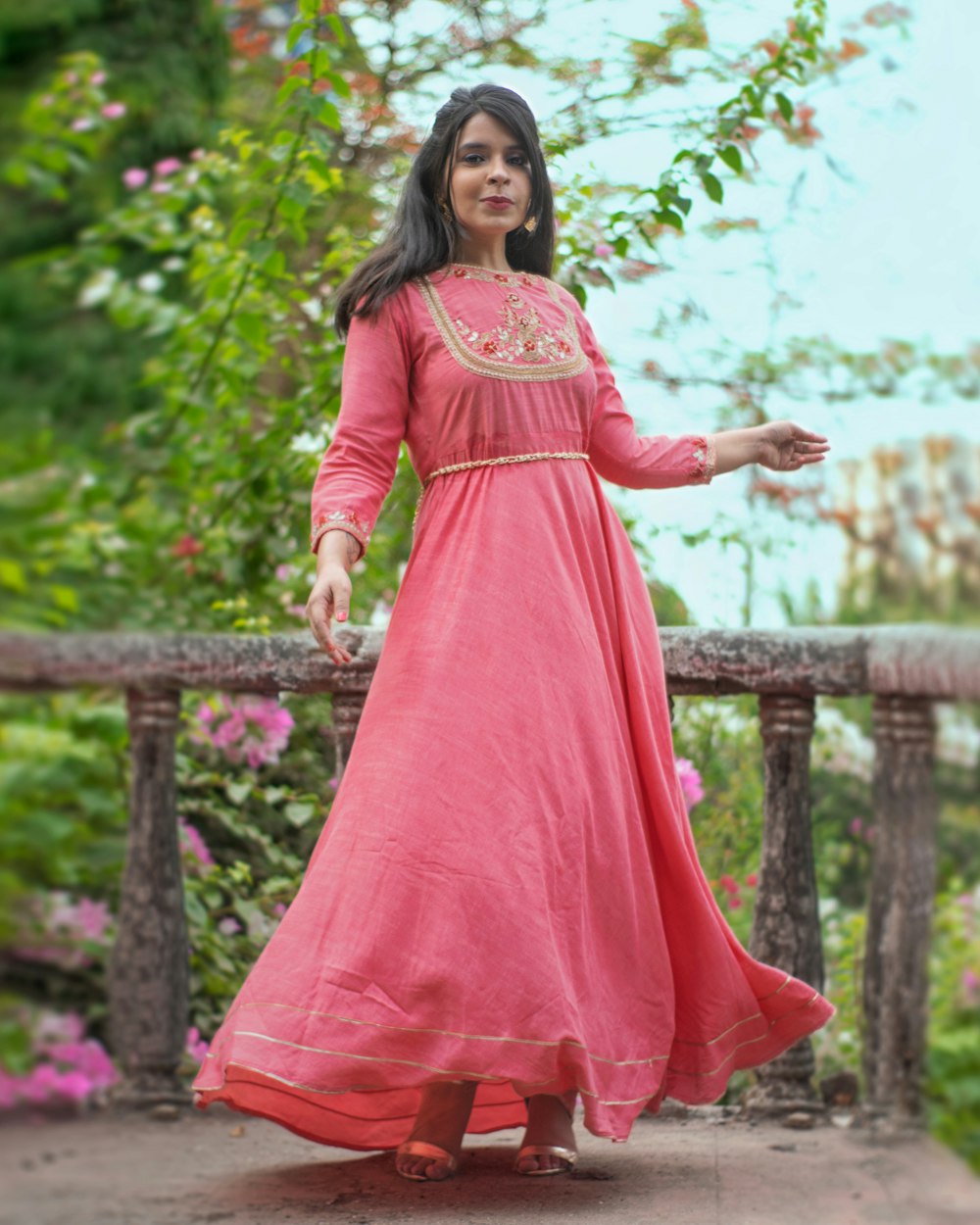 a woman in a pink dress standing on a bridge