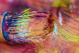 Close-up of a paintbrush loaded with vibrant color, poised over a textured wall.