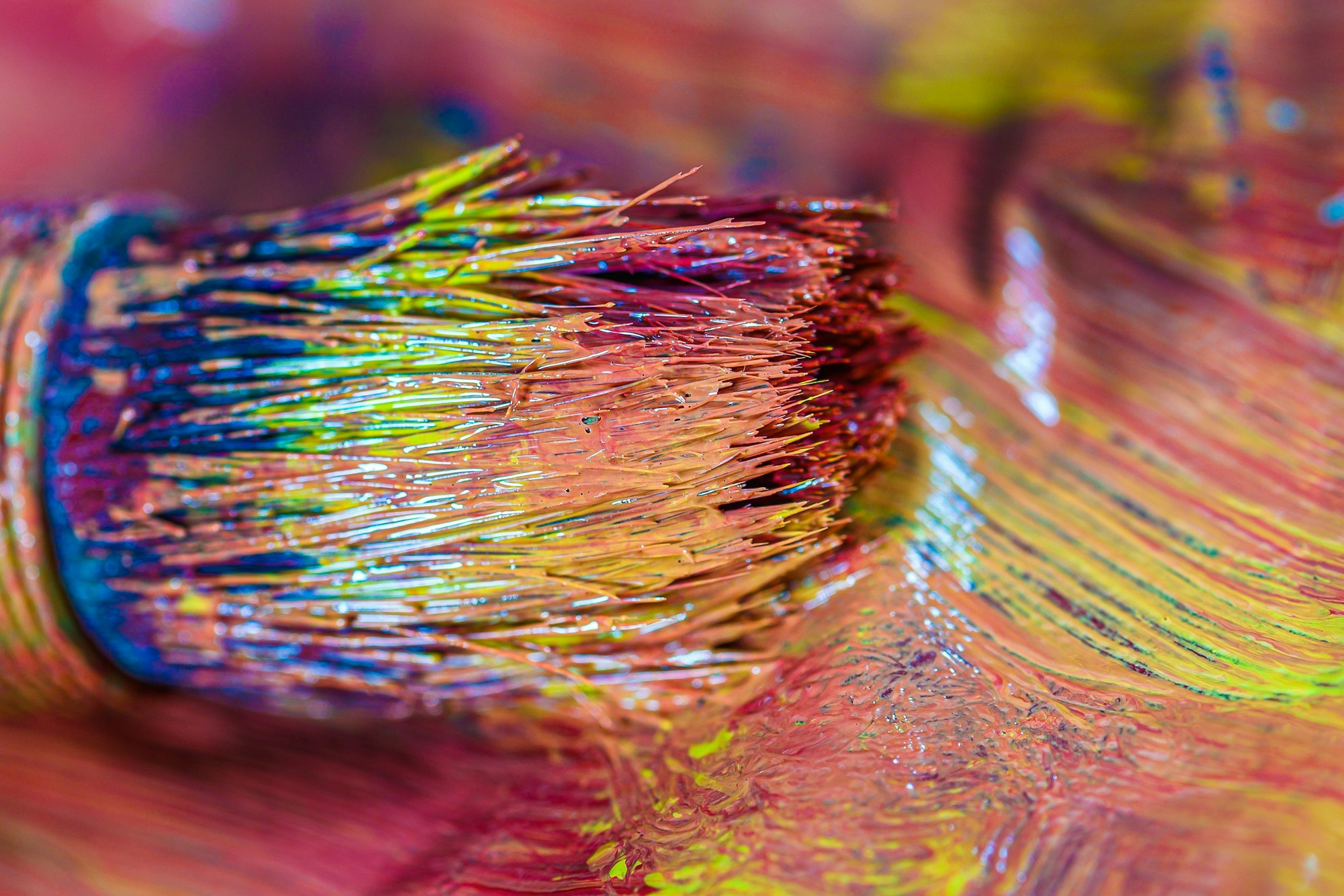 Close up image of a paint brush with lots of different colours on i