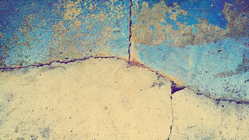 a close up of a cement surface with blue and yellow paint