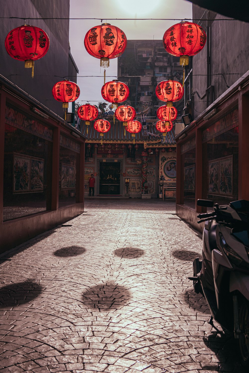 a motorcycle parked on a cobblestone street under red lanterns