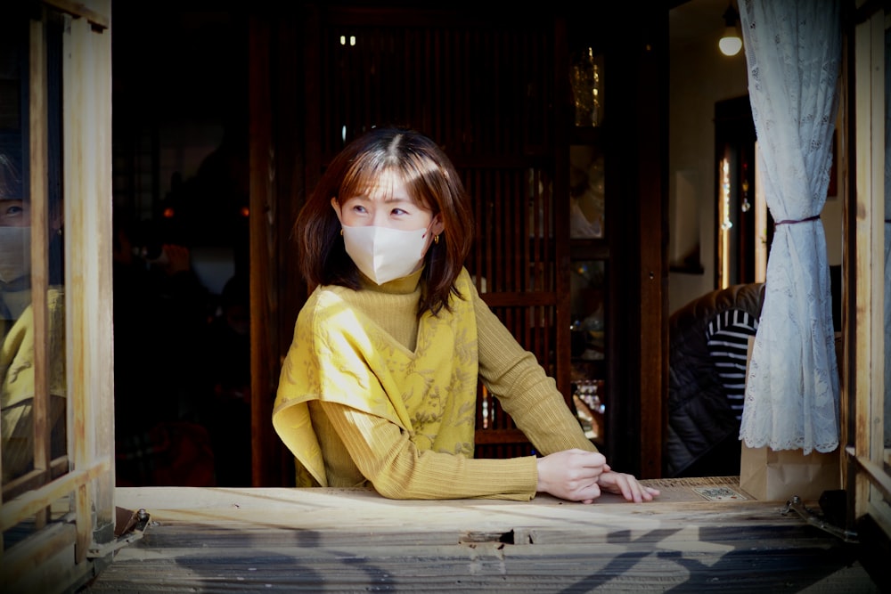 a woman wearing a face mask sitting at a table