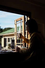A peaceful morning scene of someone journaling with a cup of tea by a sunny window.
