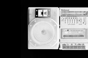 A retro-style stereo system featuring a speaker and cassette player with a graphic equalizer and multiple controls. Labels such as 'National' are visible, and the design is predominantly monochrome with a focus on contrasting tones.