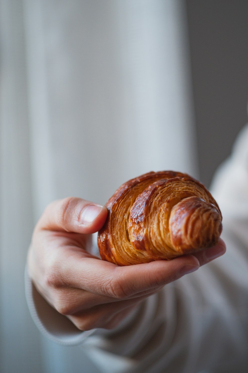 a person holding a croissant in their hand