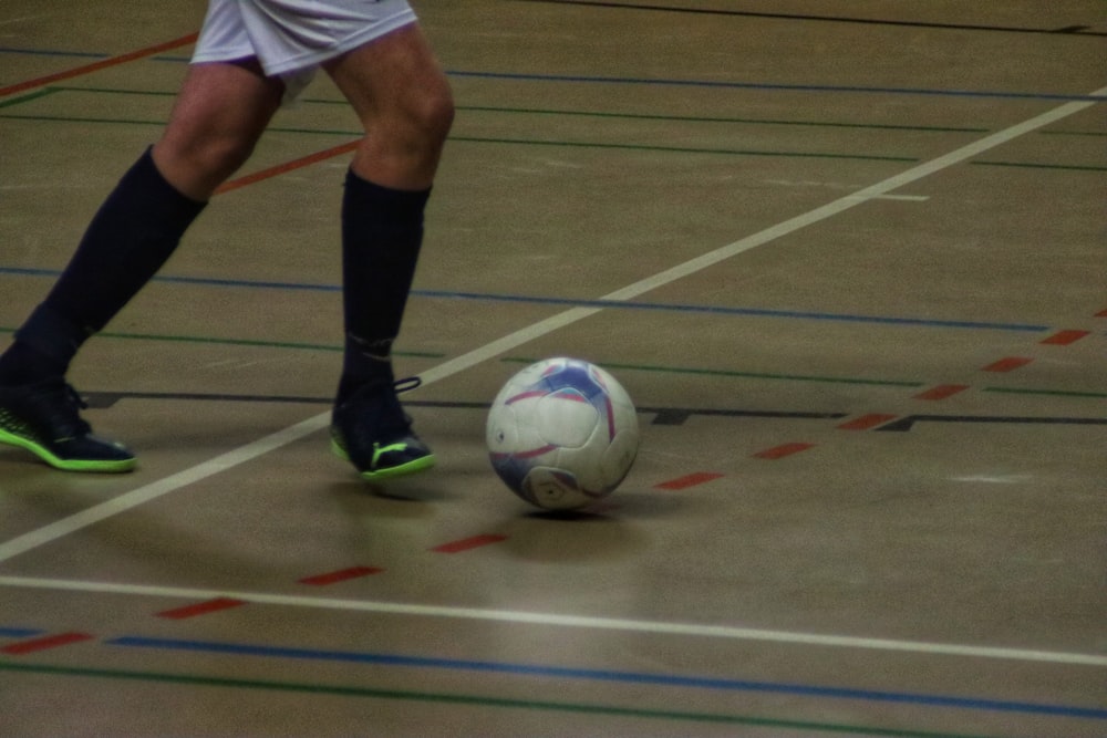 a soccer player dribbling a soccer ball on a court