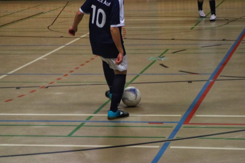 a young man kicking a soccer ball on a gym floor