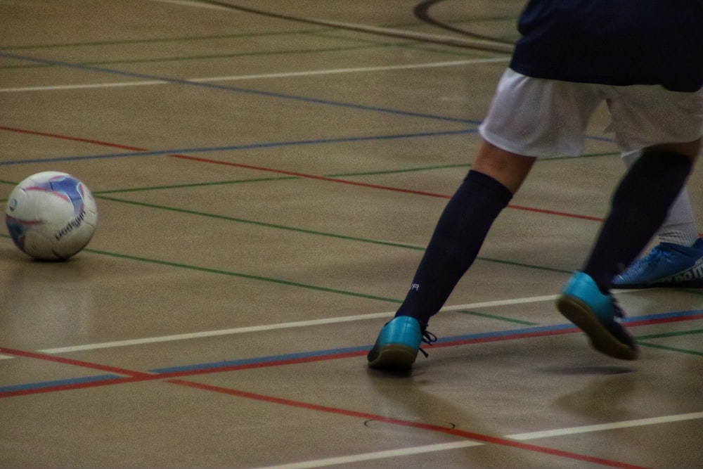 a person in blue shoes kicking a soccer ball