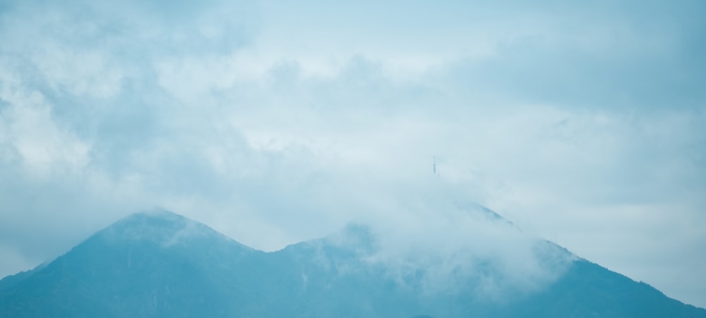 a very tall mountain covered in clouds under a blue sky