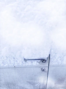 A technician unlocking a car door with professional tools on a snowy roadside.