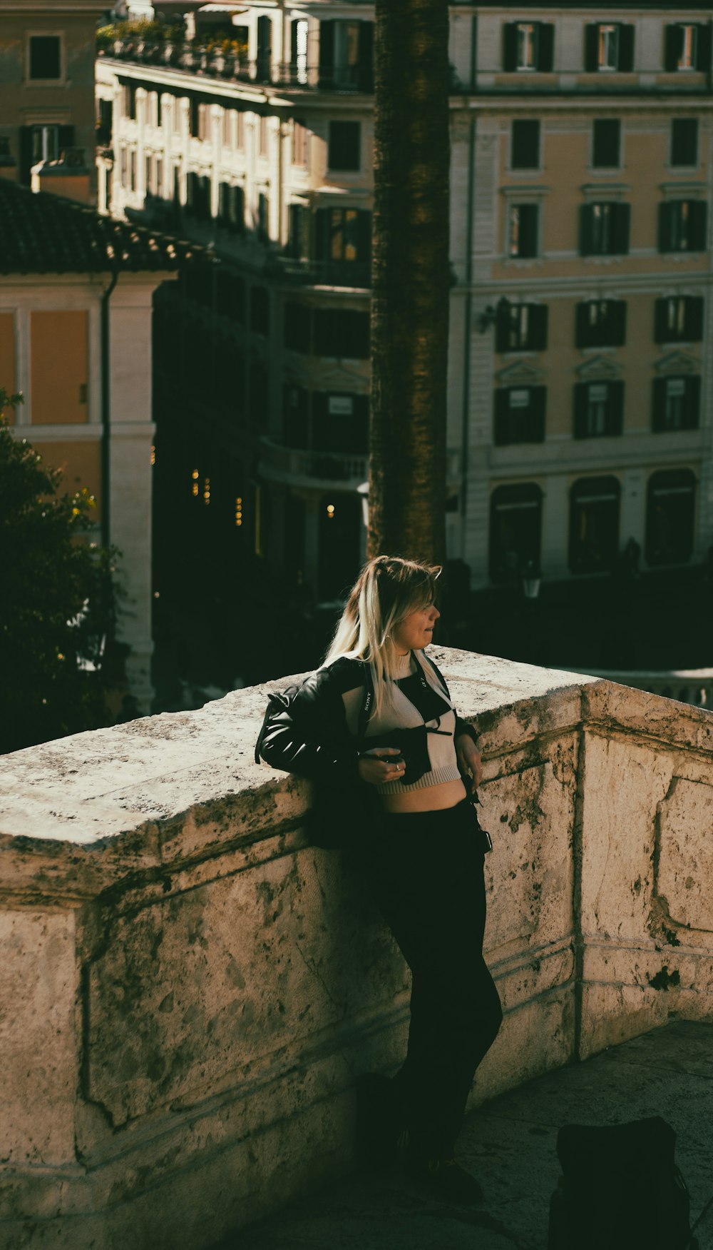 a woman leaning against a wall in a city