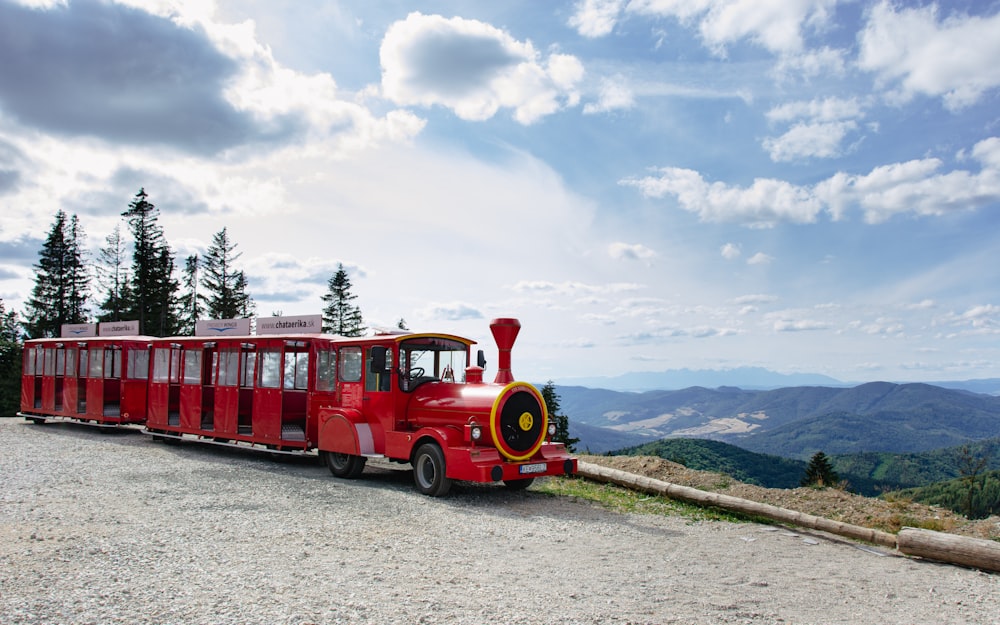 a red train is on the tracks near a mountain