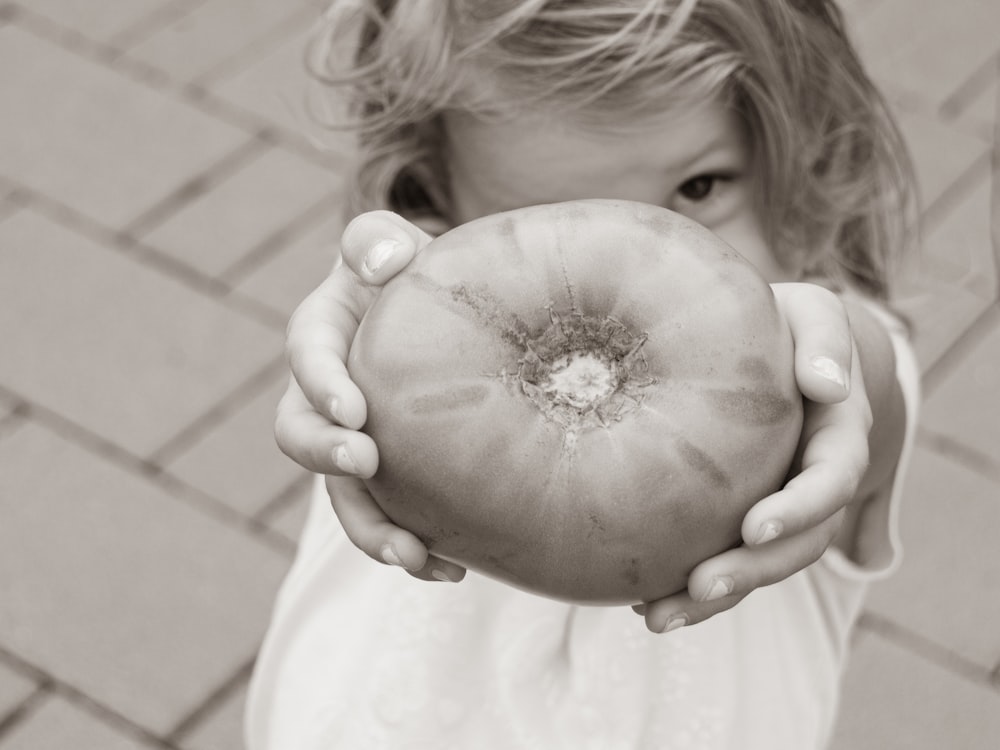 a little girl holding a tomato in her hands